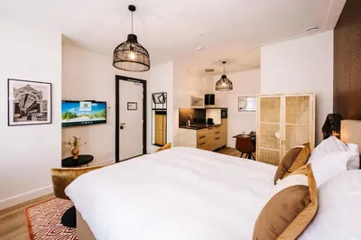 a bedroom with a large white bed and a kitchen at Boutique hotel Margretha in Zandvoort