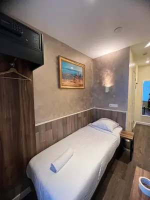a bedroom with a bed with a tv on the wall at Dam Hotel in Amsterdam