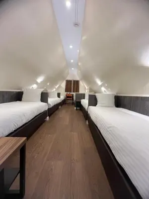 a room with three beds and a wooden table at Dam Hotel in Amsterdam