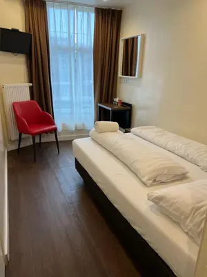a hotel room with two beds and a red chair at Dam Hotel in Amsterdam