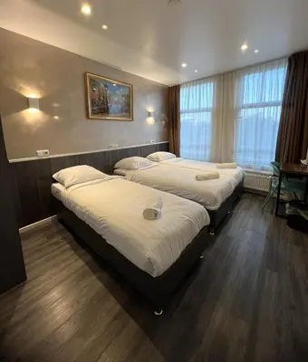 a room with three beds and a window at Dam Hotel in Amsterdam
