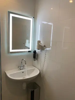a white bathroom with a sink and a mirror at Dam Hotel in Amsterdam