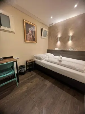 a bedroom with two beds and a painting on the wall at Dam Hotel in Amsterdam