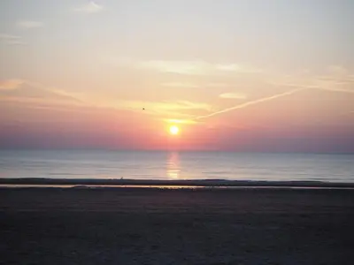 a sunset on a beach with the ocean at Apartment Seastar Zandvoort in Zandvoort
