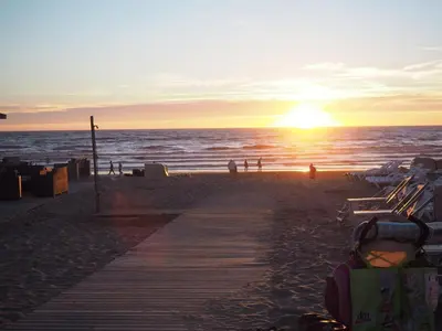 a sunset on the beach with a wooden pathway at Apartment Seastar Zandvoort in Zandvoort