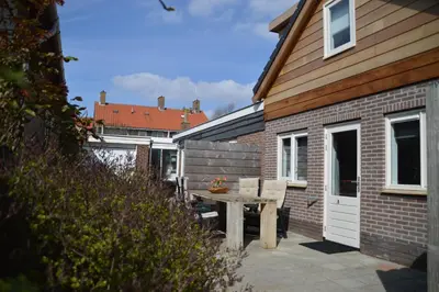 a patio with a table and chairs next to a house at Zomerhuis de Jong in Egmond aan Zee