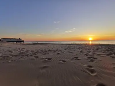 a sunset on a beach with footprints in the sand at Zomerhuis de Jong in Egmond aan Zee