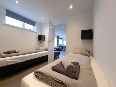 a bedroom with two beds and a tv on the wall at Zomerhuis de Jong in Egmond aan Zee