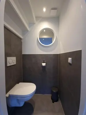a bathroom with a toilet and a round mirror at Zomerhuis de Jong in Egmond aan Zee