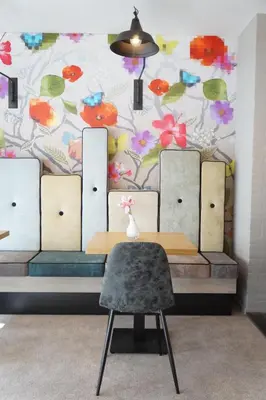 a table and a chair in front of a wall with flowers at Landgoed ISVW in Leusden