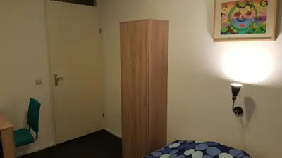 a room with a bed and a wooden cabinet at Quiet spacious room in Amsterdam