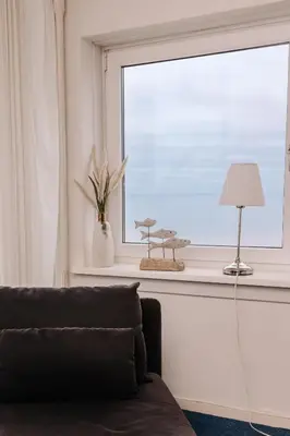 a living room with a window with a couch and a lamp at De Steltloper in Zandvoort