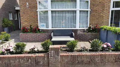 a chair sitting in front of a building with flowers at Guesthouse Zandvoort in Zandvoort