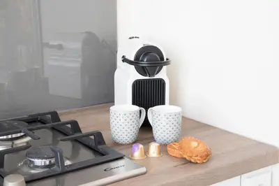 a counter with two coffee cups and a doughnut on it at kustappartementenkatwijk in Katwijk aan Zee
