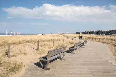 three benches on a boardwalk at the beach at kustappartementenkatwijk in Katwijk aan Zee