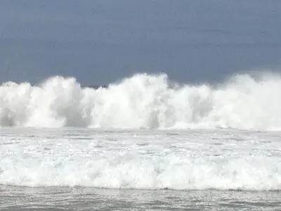 a large wave in the ocean with a surfer at De Vuurdoorn in Bergen