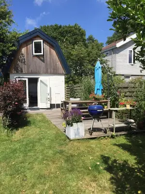 a backyard with a picnic table and a blue umbrella at De Vuurdoorn in Bergen