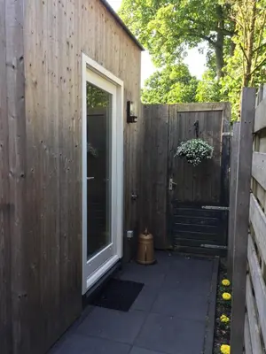 a patio with a door and a wooden fence at Het Hart in Bergen