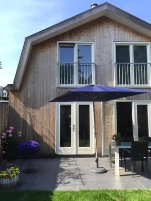 a blue umbrella in front of a house at Het Hart in Bergen