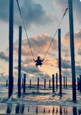 a person on a swing over the water at Huisje Britt met grote tuin en veel privacy in Dirkshorn