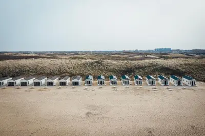 a row of beach huts on a sandy beach at Logeren aan Zee in Katwijk aan Zee