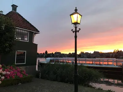 a street light with a sunset in the background at Stay overnight at Windmill Village Zaanse Schans - Amsterdam in Zaandam