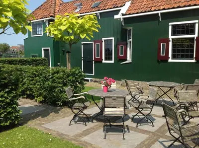 a table and chairs in front of a green building at Stay overnight at Windmill Village Zaanse Schans - Amsterdam in Zaandam