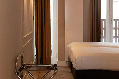 a room with a bed and a chair next to a window at Midtown Hotel Twin Studio in Amsterdam