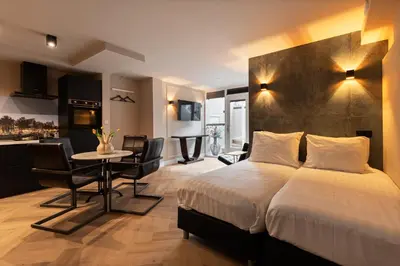 a bedroom with a bed and a table and a kitchen at Midtown Hotel Royal Room in Amsterdam