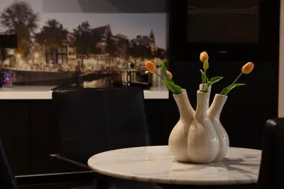 two white vases sitting on a table with flowers in them at Midtown Hotel Royal Room in Amsterdam