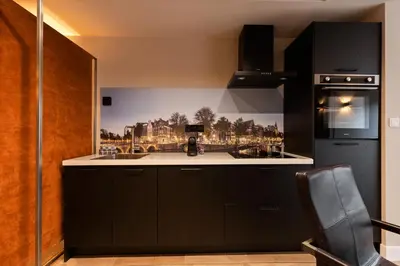 a kitchen with black cabinets and a black refrigerator at Midtown Hotel Royal Room in Amsterdam