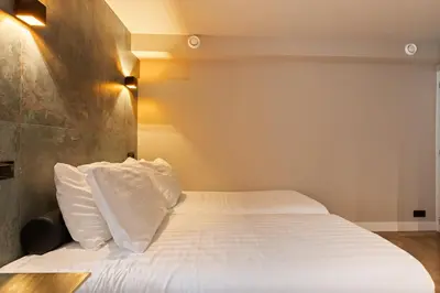 a bedroom with a bed with white sheets and pillows at Midtown Hotel Royal Room in Amsterdam