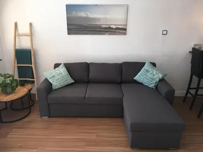 a living room with a gray couch and a ladder at Annadora Beach House - Private Parking in Zandvoort