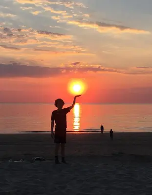 a person standing on the beach holding up the sun at Annadora Beach House - Private Parking in Zandvoort