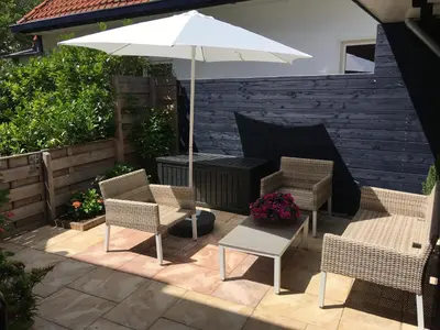 a patio with two chairs and an umbrella at Annadora Beach House - Private Parking in Zandvoort