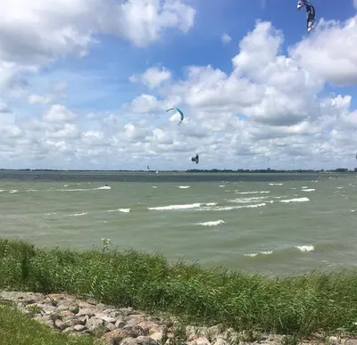 two kites flying over a large body of water at Lekerweg 32 in Wijdenes