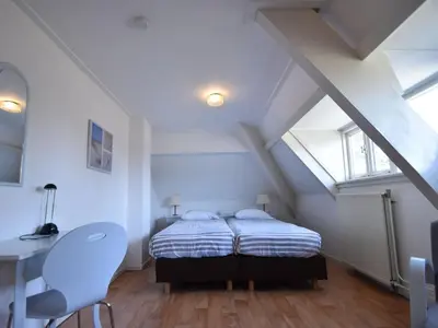 a bedroom with a bed and a desk in a attic at Holiday Home Bergen near Beach & Dunes in Bergen aan Zee