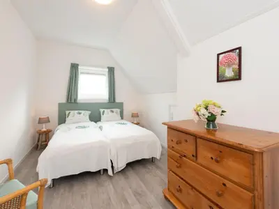 a bedroom with a white bed and a wooden dresser at Apartment in Schoorl near Dunes in Schoorl
