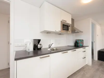 a white kitchen with a sink and a microwave at Apartment in Schoorl near Dunes in Schoorl
