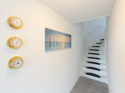 a staircase in a house with clocks on the wall at Apartment in Schoorl near Dunes in Schoorl