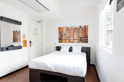 a bedroom with a bed and a painting on the wall at easyHotel Amsterdam City Centre South in Amsterdam