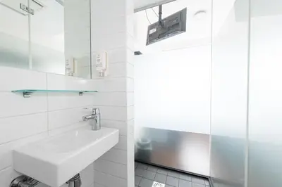 a white bathroom with a sink and a shower at easyHotel Amsterdam City Centre South in Amsterdam