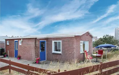 a small brick house with a blue door and a table at Huisje Zand En Water in Egmond aan Zee