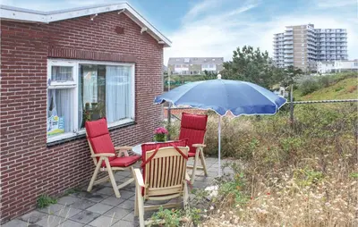 three chairs and a table with an umbrella on a patio at Huisje Zand En Water in Egmond aan Zee