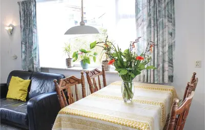a dining room table with a vase of flowers on it at Huisje Zand En Water in Egmond aan Zee