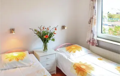 two twin beds in a room with a vase of flowers at Huisje Zand En Water in Egmond aan Zee