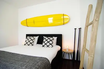 a yellow surfboard hanging on a wall above a bed at Hotel Zand in Zandvoort