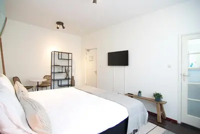 a bedroom with a white bed and a television at Hotel Zand in Zandvoort
