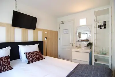a bedroom with a bed with a television on the wall at Hotel Zand in Zandvoort