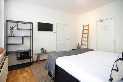 a bedroom with a white bed and a television at Hotel Zand in Zandvoort